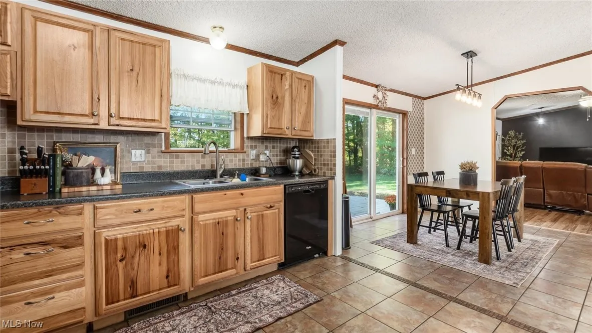 Kitchen featuring decorative backsplash, ornamental molding, a textured ceiling, black dishwasher, and light tile patterned flooring