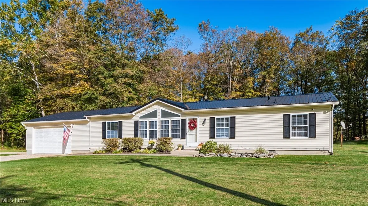 Single story home featuring a front lawn, an attached garage, crawl space, a metal roof, and driveway