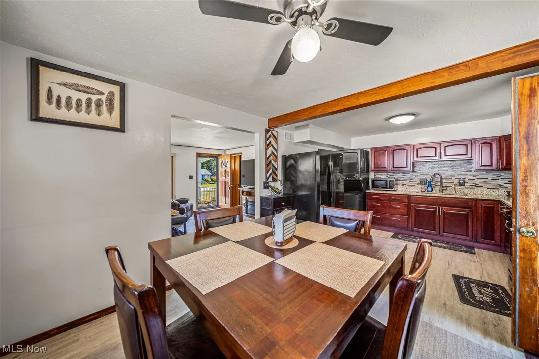 Dining room with light wood-type flooring, beamed ceiling, ceiling fan, and a textured ceiling