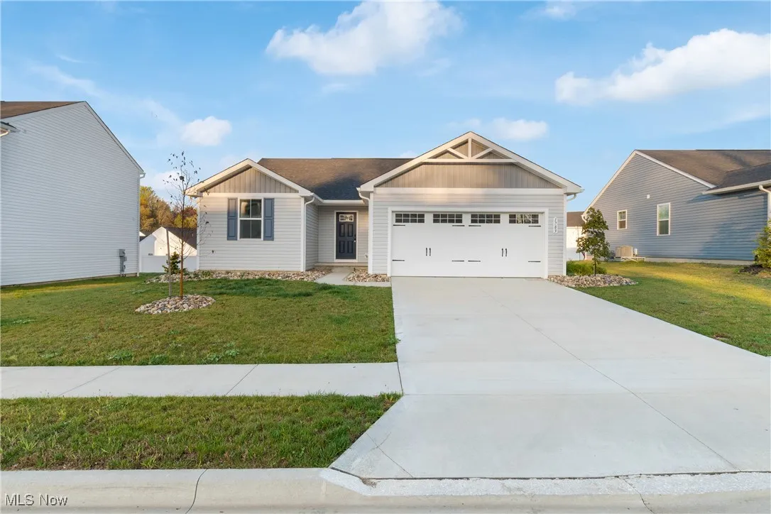 Craftsman-style house featuring board and batten siding, driveway, a front lawn, and a garage