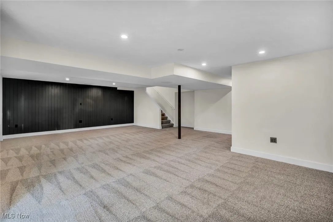 Finished below grade area featuring light colored carpet, recessed lighting, and stairway
