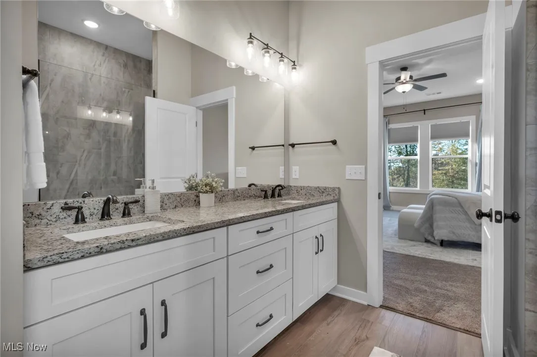 Bathroom featuring ensuite bath, double vanity, light wood finished floors, a tile shower, and recessed lighting