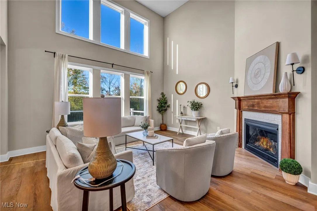 Living area featuring a high ceiling, light wood-style flooring, and a glass covered fireplace