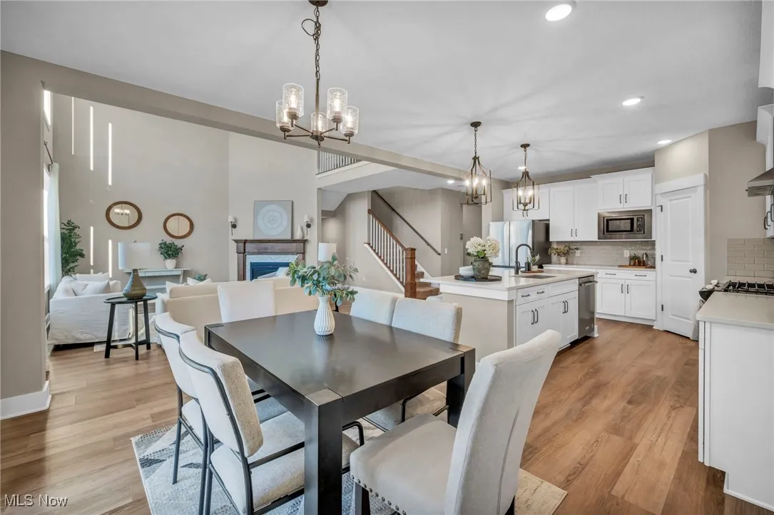 Dining space with stairway, a fireplace, light wood-style flooring, a chandelier, and recessed lighting