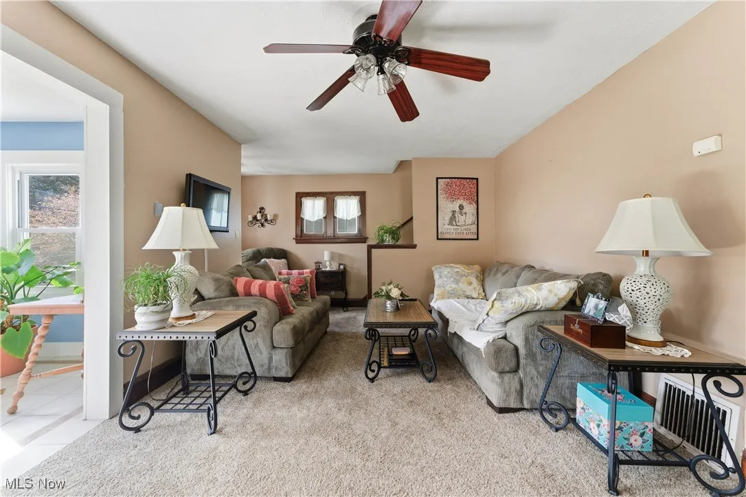 Living area with light carpet and ceiling fan