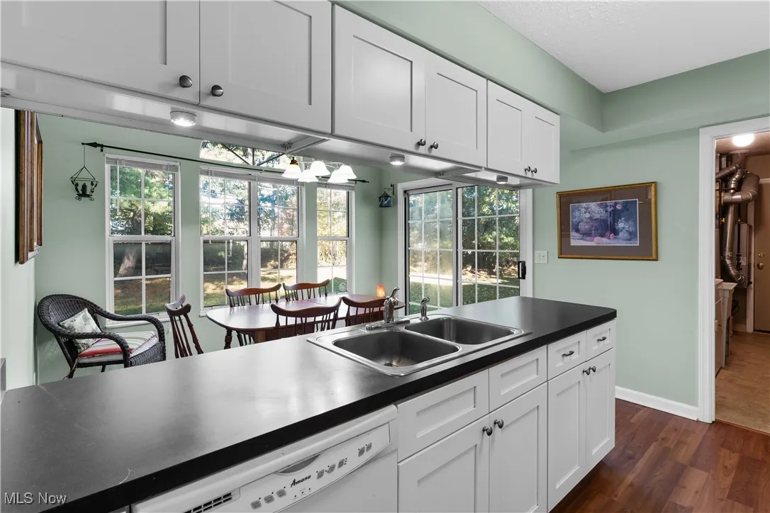 Kitchen with white cabinets, dark countertops, white dishwasher, and a textured ceiling