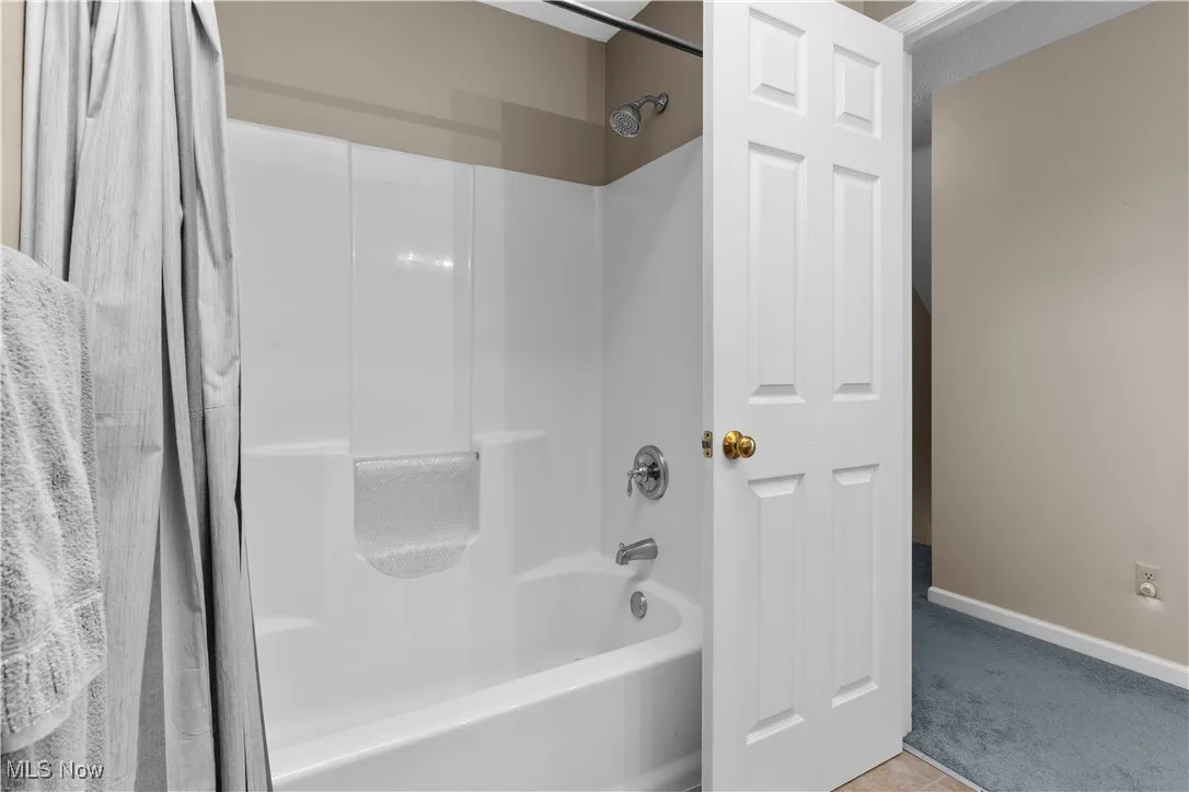 Bathroom #2 with shower /bathtub combination with curtain and light tile patterned floors