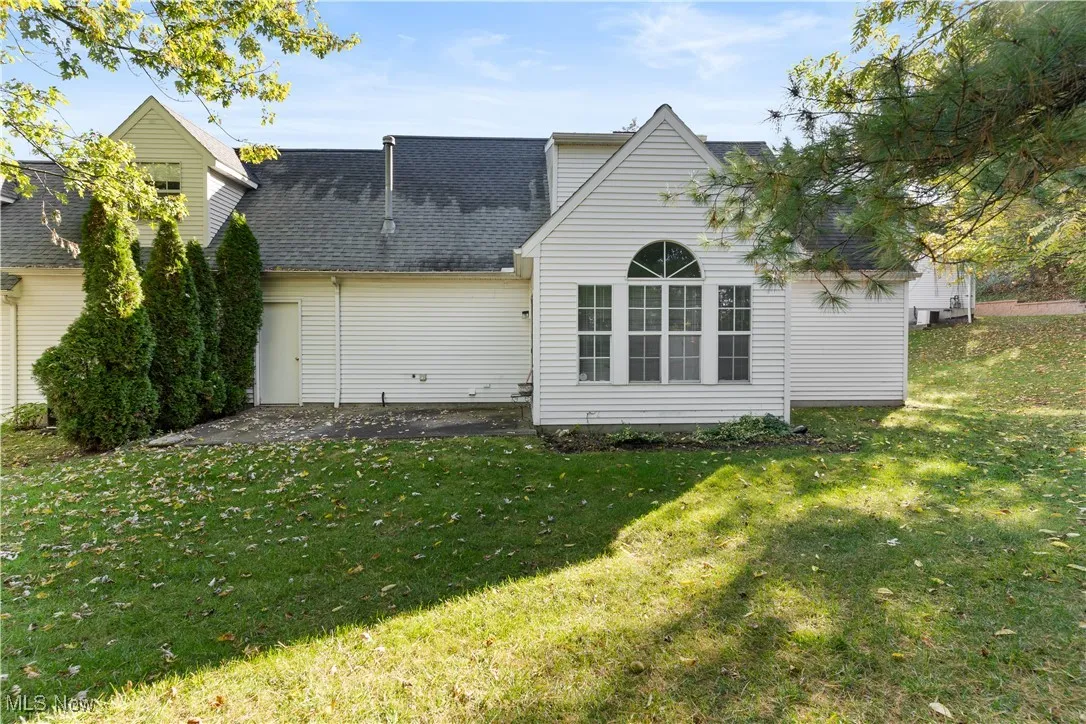 Back of house featuring a yard and roof with shingles