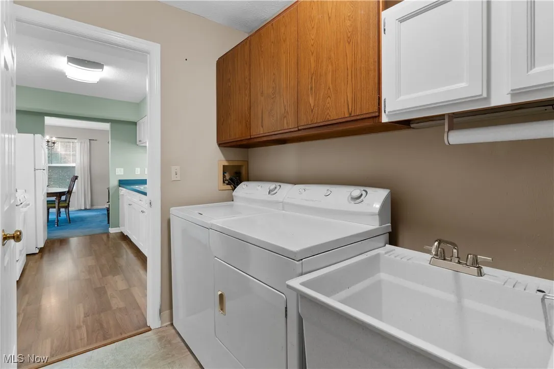 Laundry area with cabinet space, separate washer and dryer, and light wood finished floors