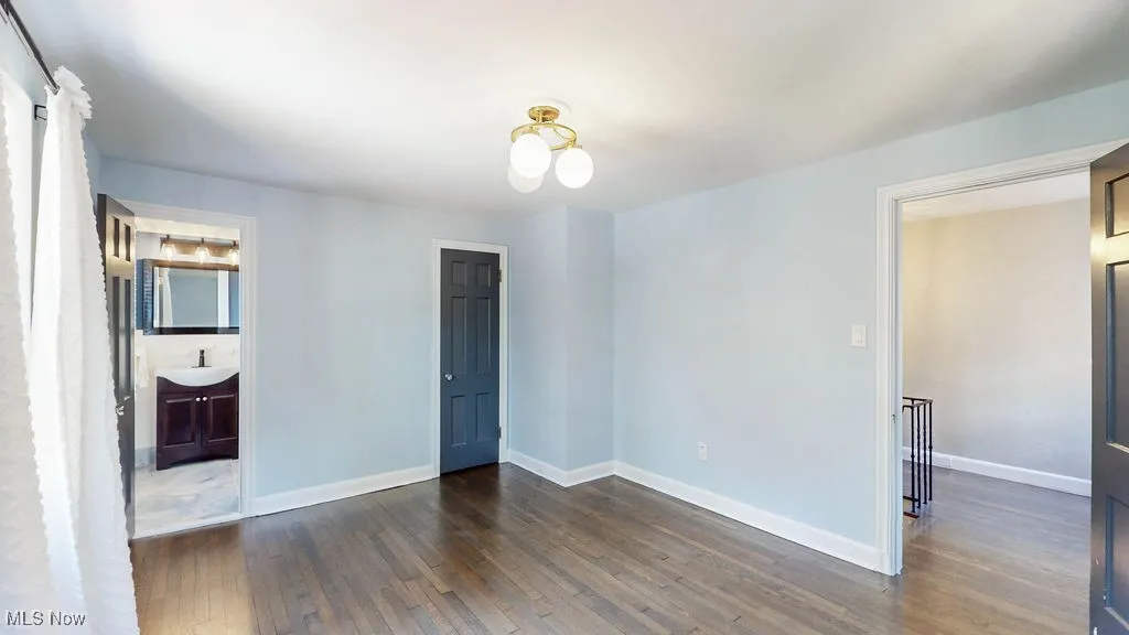 Unfurnished bedroom featuring dark wood-style flooring and baseboards