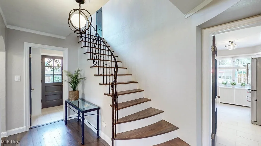 Staircase featuring ornamental molding and wood finished floors