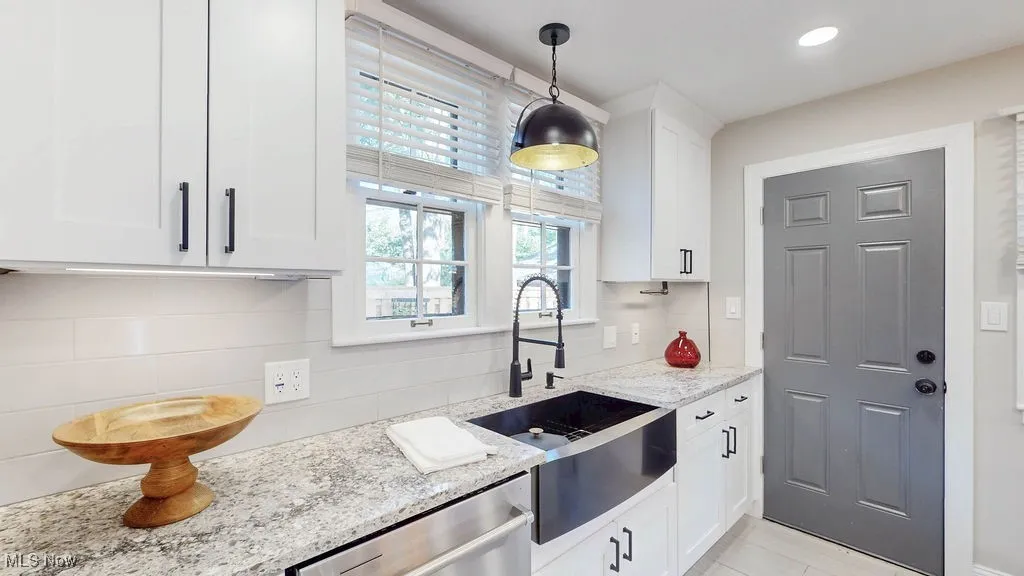 Kitchen featuring decorative backsplash, white cabinetry, light stone countertops, pendant lighting, and recessed lighting
