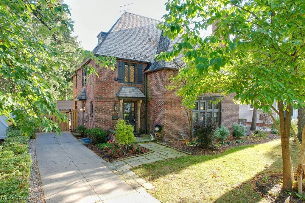 Tudor home featuring a high end roof, brick siding, and a front lawn