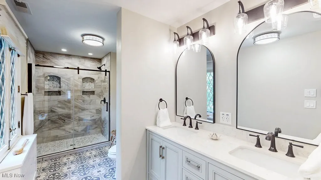 Bathroom with double vanity, a stall shower, light tile patterned floors, and recessed lighting