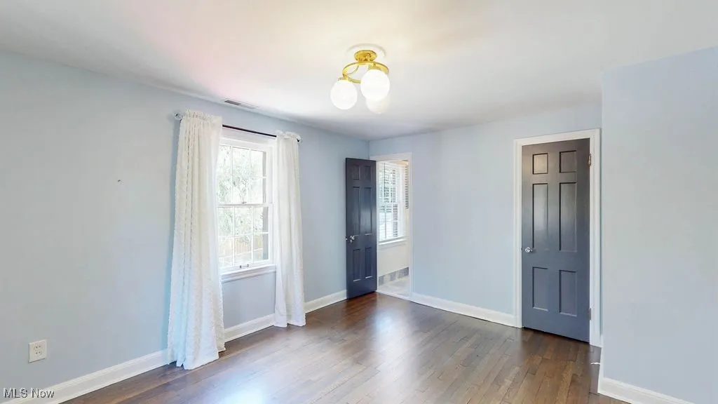 Empty room featuring dark wood finished floors and baseboards