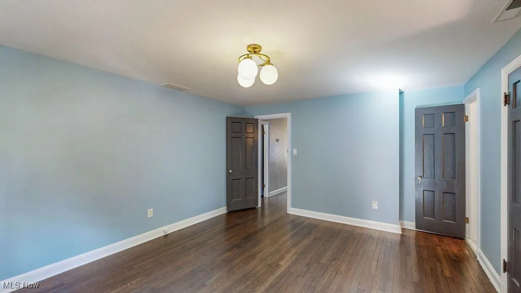 Unfurnished bedroom featuring baseboards and dark wood finished floors