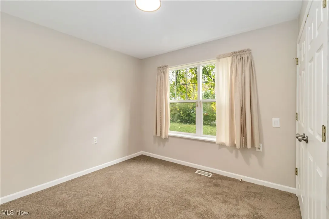 Carpeted spare room featuring baseboards