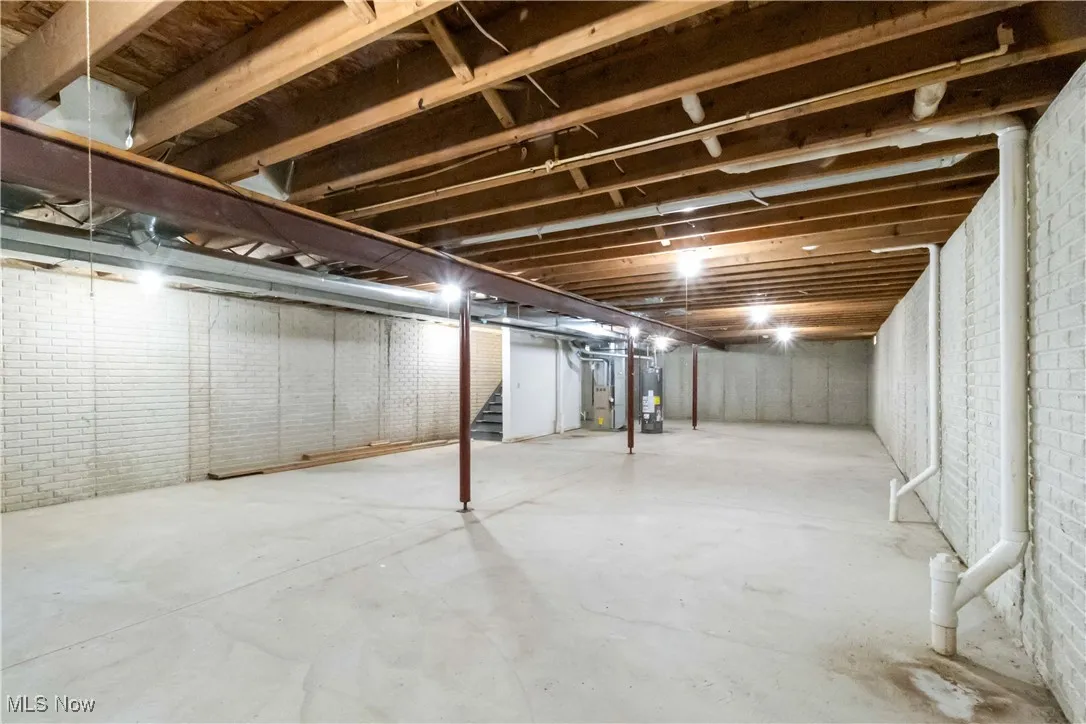 Unfinished basement featuring stairs, gas water heater, and heating unit