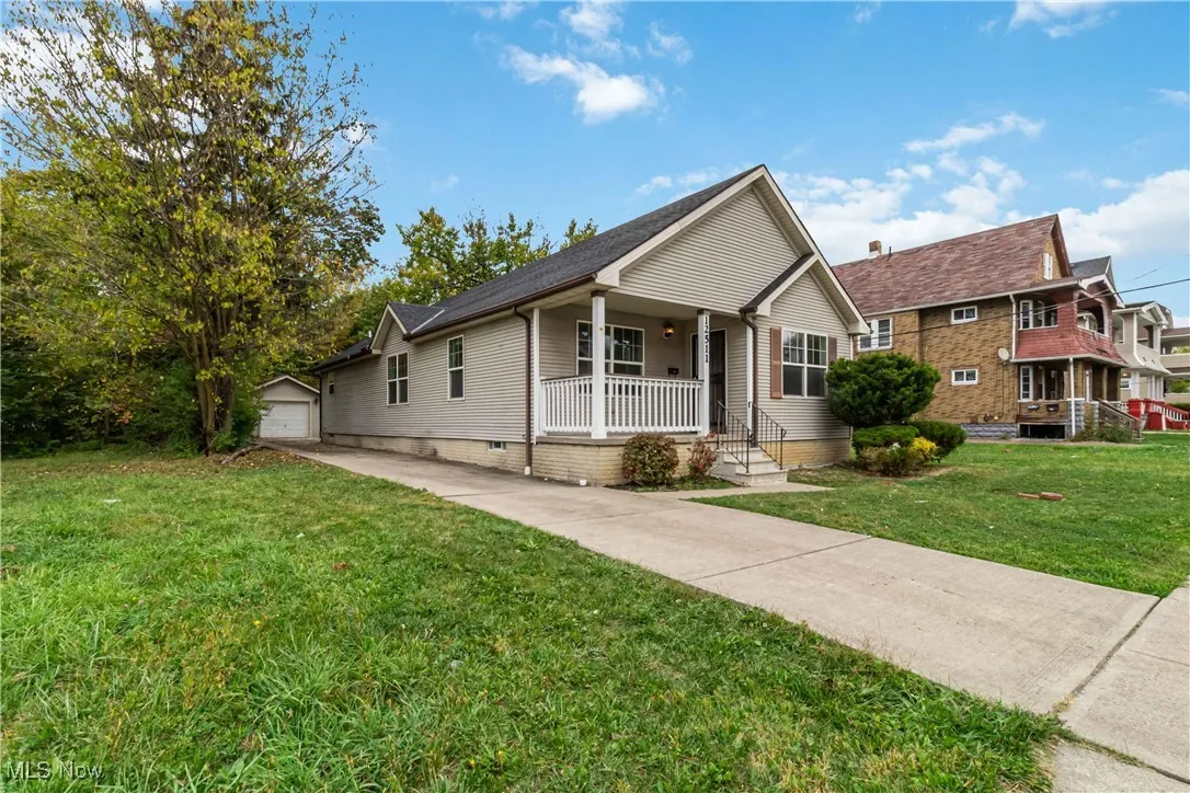View of front of property featuring a front yard, covered porch, a garage, and driveway
