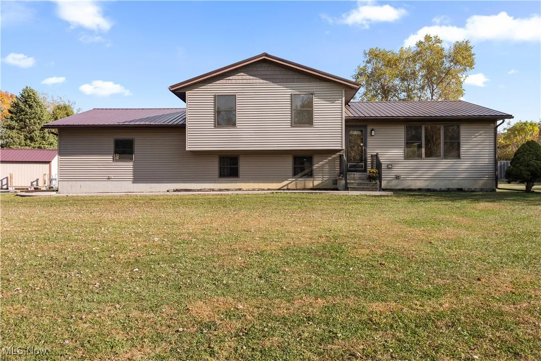 Rear view of house with a metal roof and a lawn