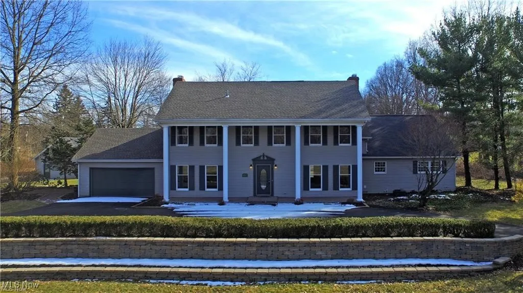 View of front of property featuring driveway, a garage, a chimney, and a patio