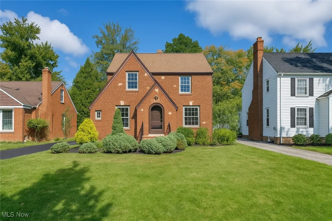 English style home with a front yard and brick siding