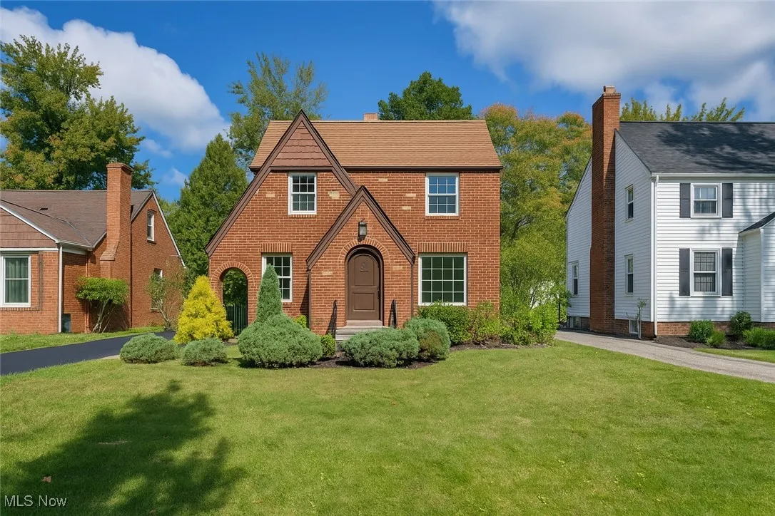 English style home featuring a front yard and brick siding