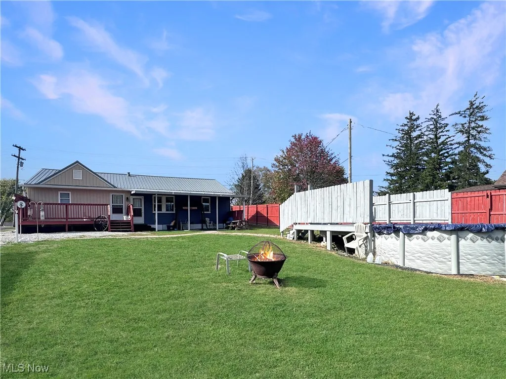 Fenced backyard with an outdoor fire pit and a wooden deck