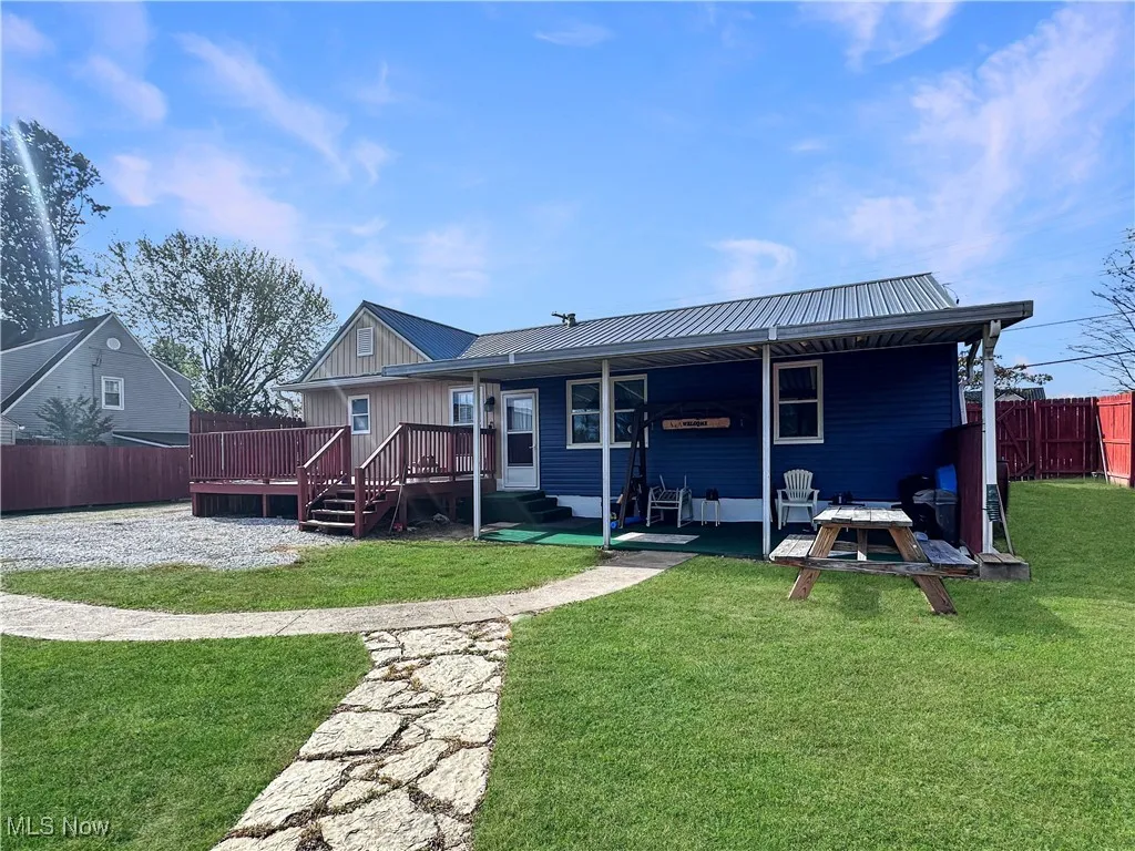 Back of property with a metal roof, a deck, and a patio area