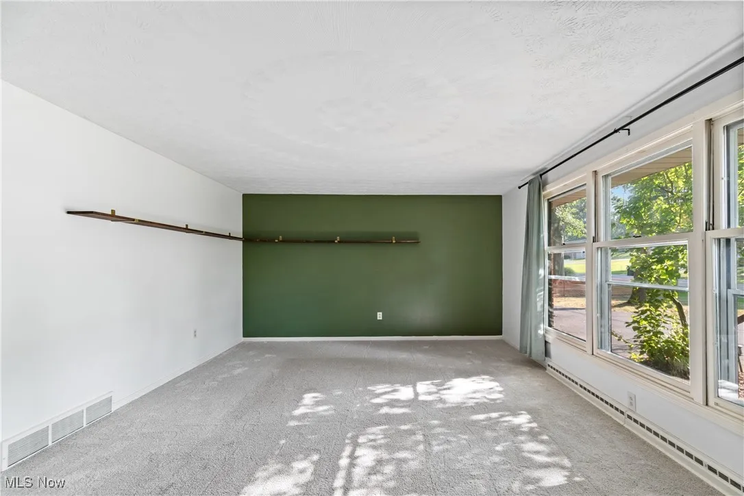 Spare room with a baseboard heating unit, carpet, and a textured ceiling