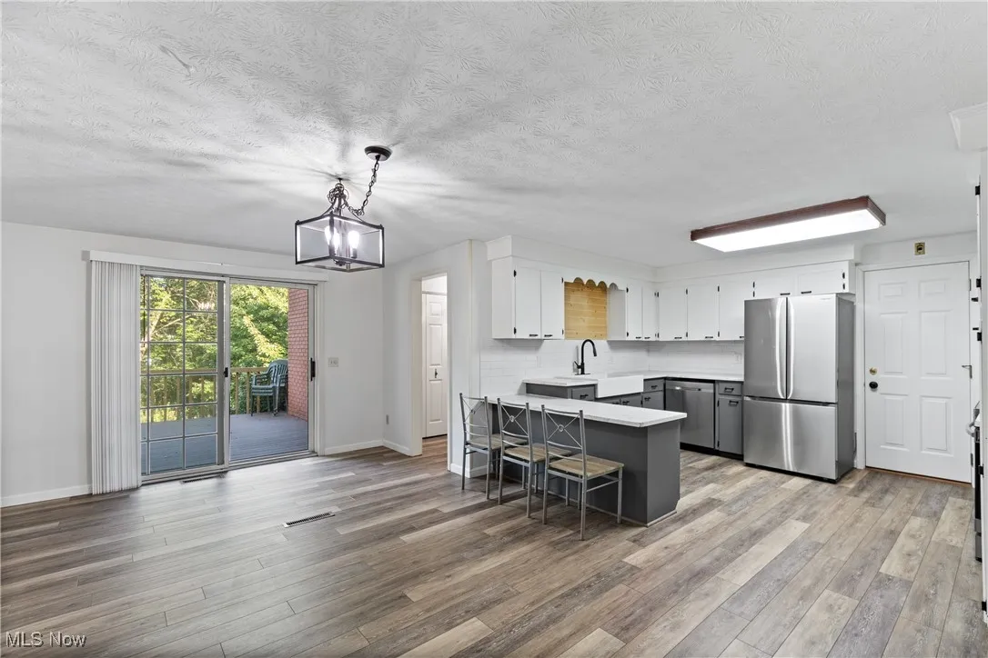 Kitchen featuring stainless steel appliances, a peninsula, gray cabinets, hanging light fixtures, and a textured ceiling