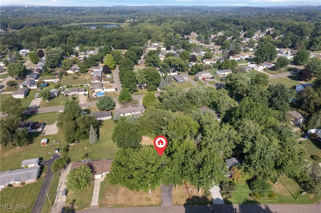 Aerial view of property and surrounding area featuring nearby suburban area and a forest