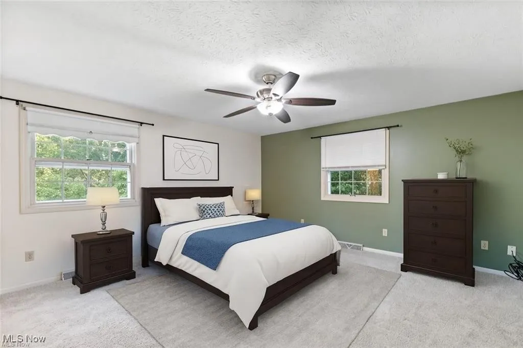 Bedroom with light colored carpet, a ceiling fan, and a textured ceiling