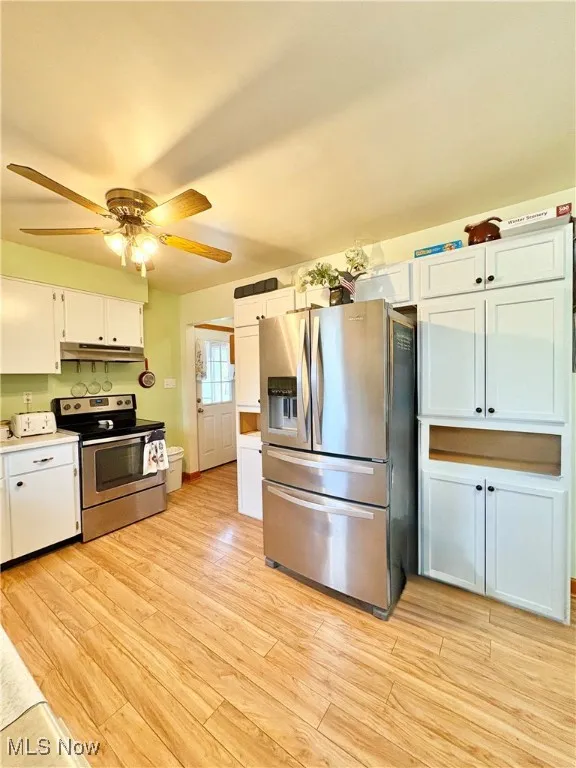 Kitchen featuring appliances with stainless steel finishes, white cabinets, light wood-style flooring, and ceiling fan