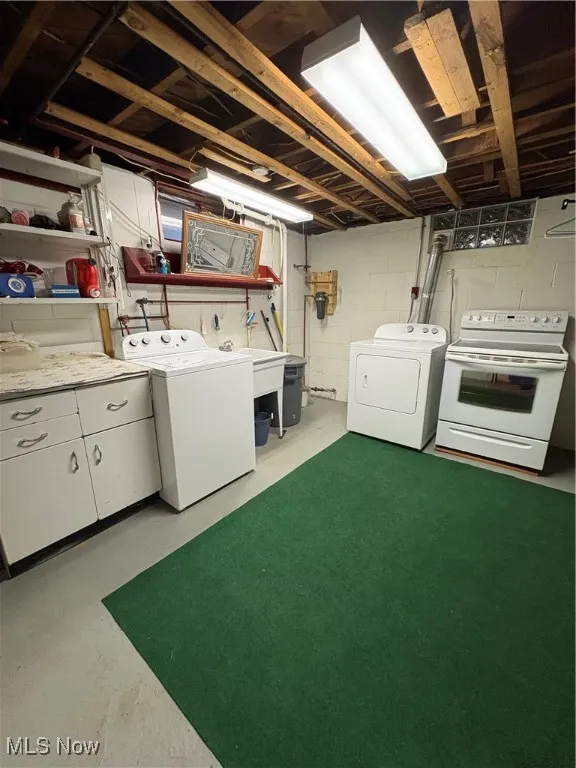 Laundry room featuring separate washer and dryer, concrete flooring, and cabinet space