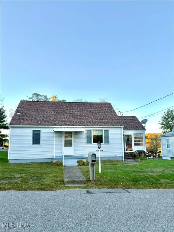 View of front of property with a front yard, a shingled roof, and entry steps