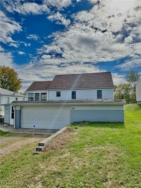 Back of house with a garage, driveway, and a yard