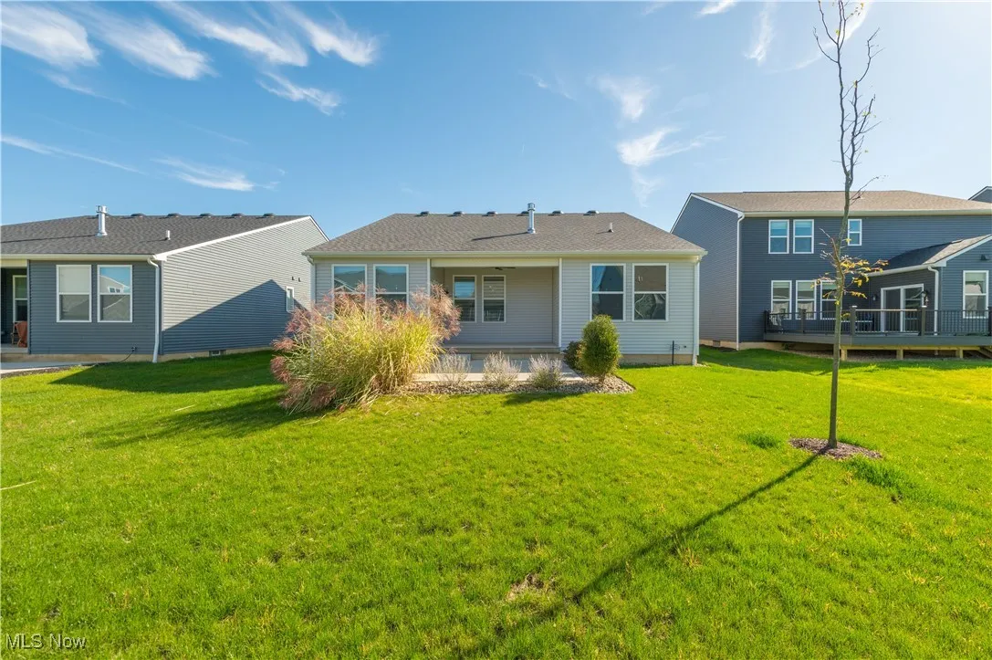 Rear view of house featuring a patio, a lawn, and a wooden deck