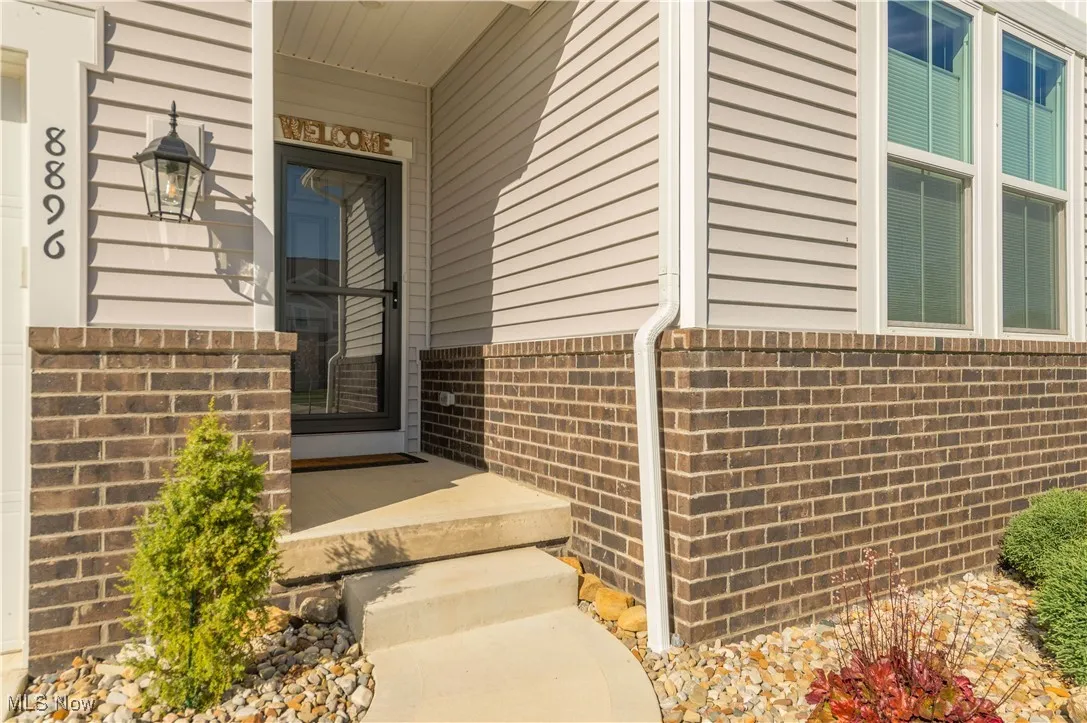 Doorway to property with brick siding and a porch