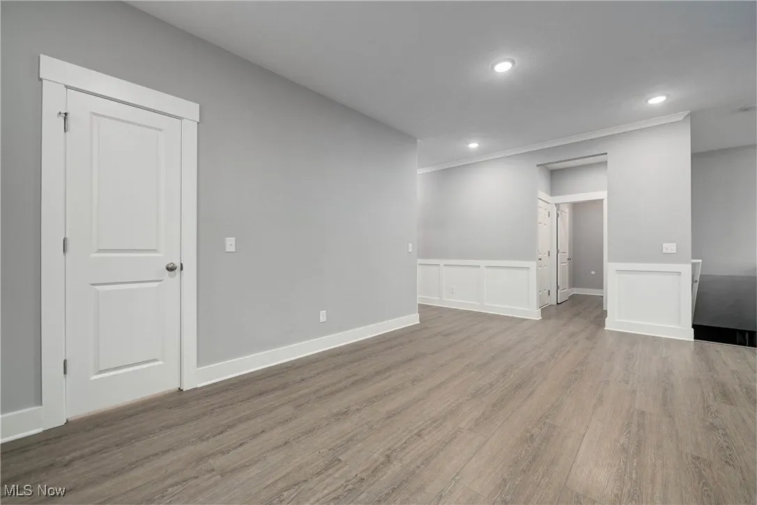 living room with wood finished floors, recessed lighting, a wainscoted wall, and a decorative wall