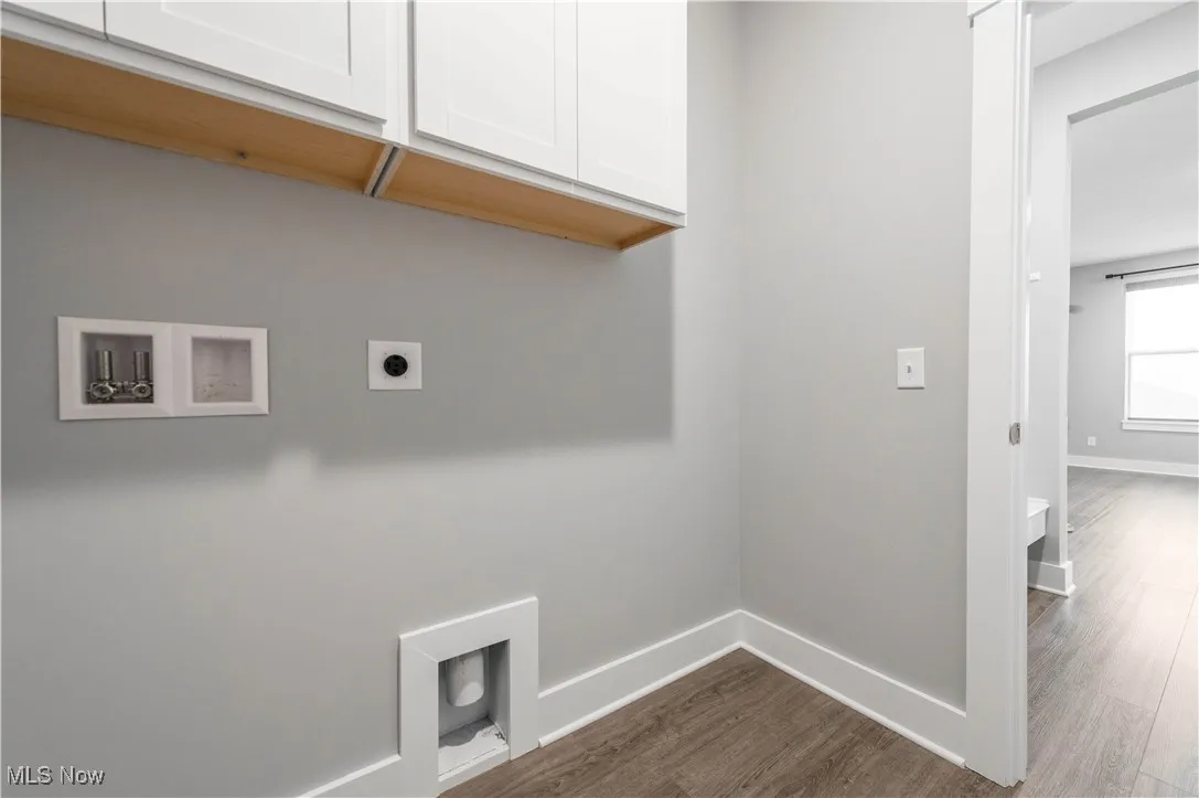 Laundry room with dark wood-type flooring, cabinet space, hookup for an electric dryer, and washer hookup
