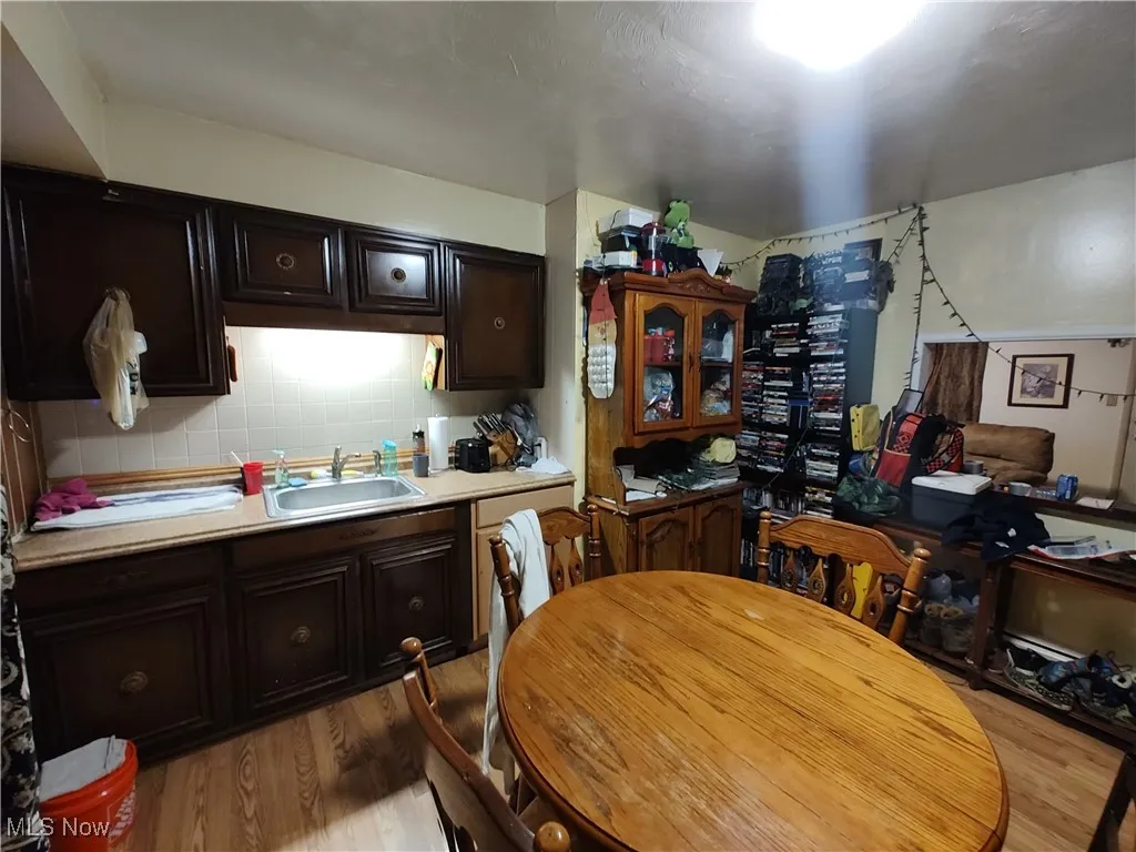 Kitchen featuring light countertops, dark brown cabinetry, light wood finished floors, tasteful backsplash, and dishwashing machine