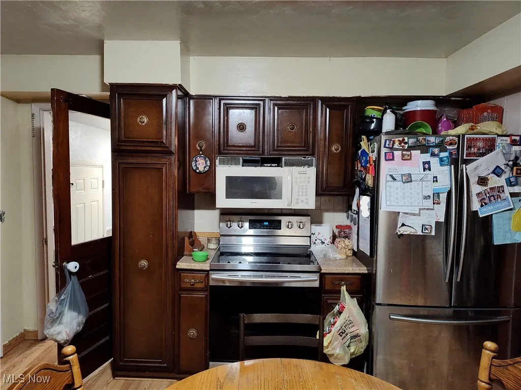 Kitchen featuring appliances with stainless steel finishes, dark brown cabinetry, and wood finished floors