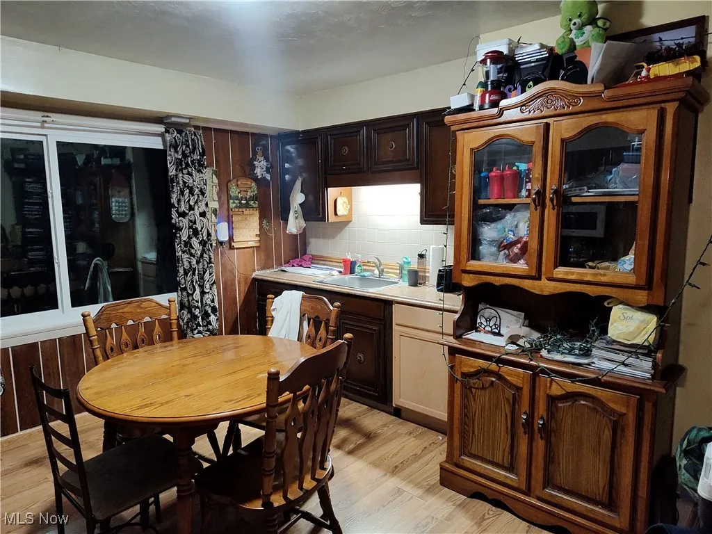 Kitchen featuring tasteful backsplash, dark brown cabinets, light wood finished floors, and light countertops