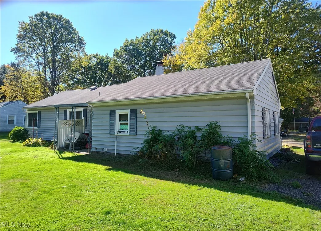 Rear view of property featuring a yard, a chimney, and roof with shingles