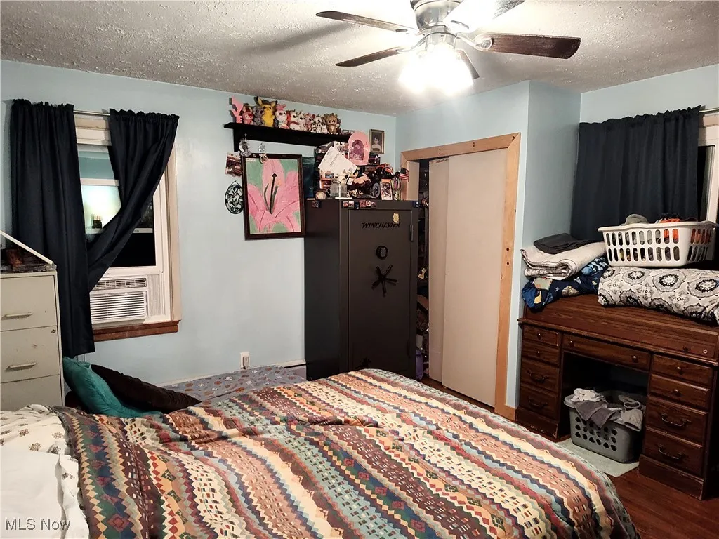 Bedroom with a textured ceiling, wood finished floors, a ceiling fan, and a closet