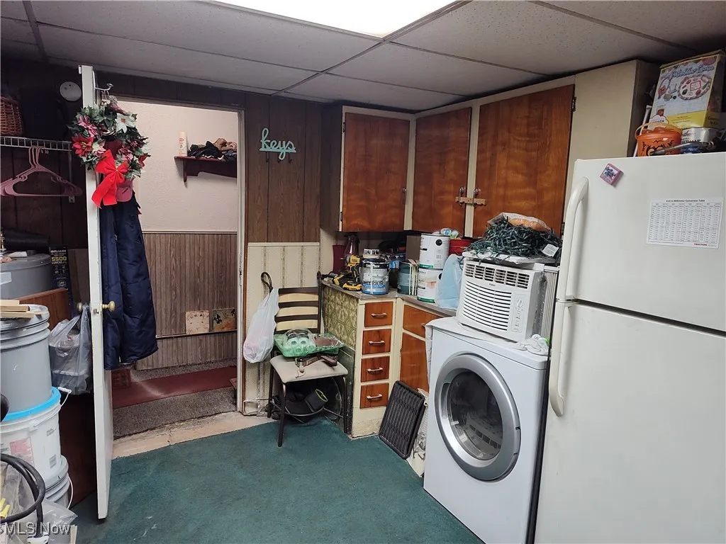 Laundry room featuring a drop ceiling, washer / clothes dryer, and wooden walls