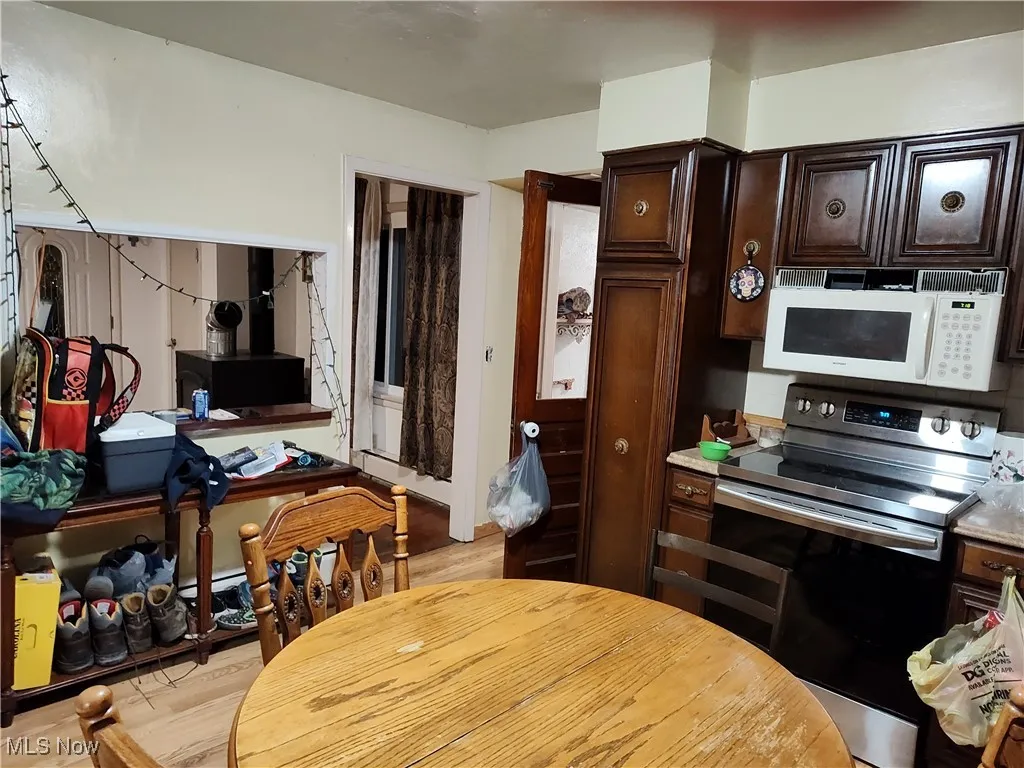 Kitchen featuring dark brown cabinetry, stainless steel electric range oven, white microwave, and light countertops