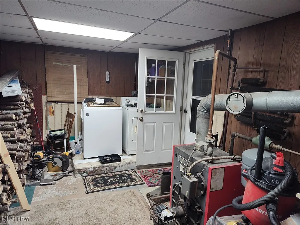 Finished basement with wooden walls, a drop ceiling, and separate washer and dryer