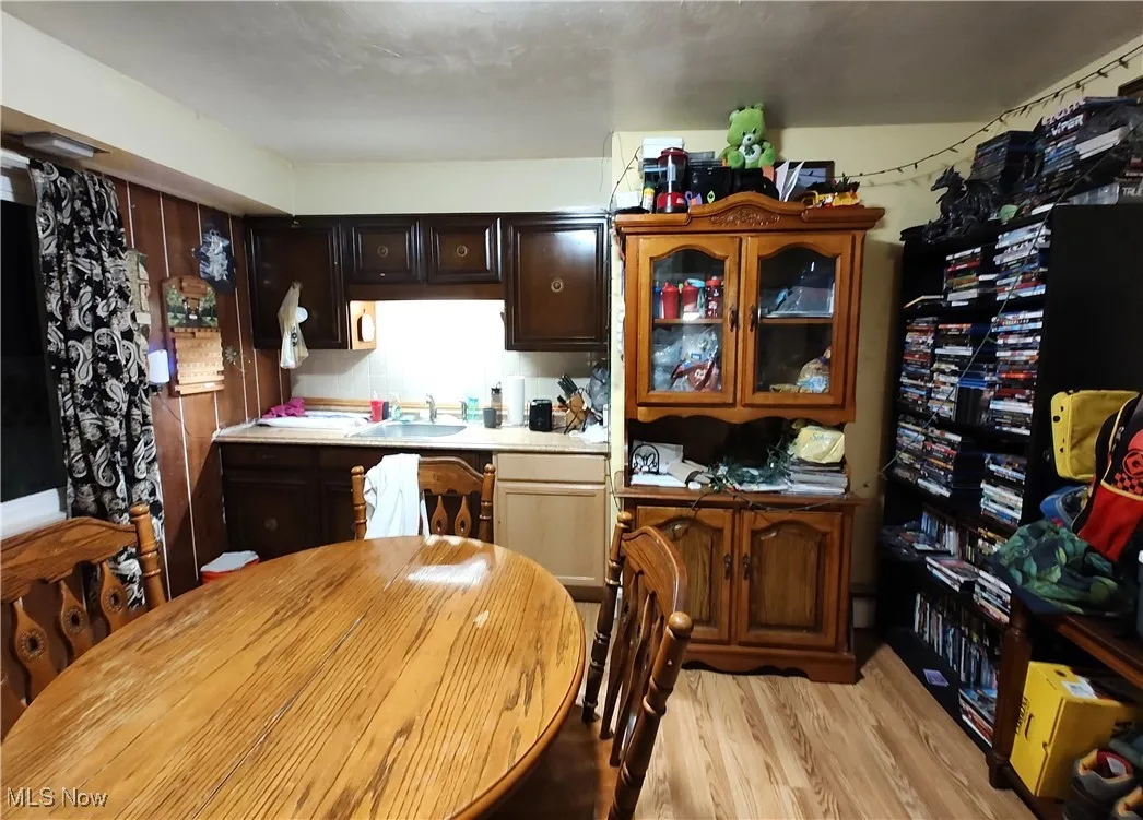 Kitchen with light wood-type flooring, dark brown cabinetry, light countertops, and glass insert cabinets
